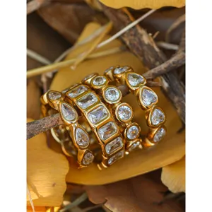 Dettaglio di eleganti anelli impilabili in acciaio dorato con brillanti pietre di zircone.