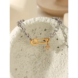Two-tone stainless steel safety pin chain bracelet with rhinestone cross pendant for women.