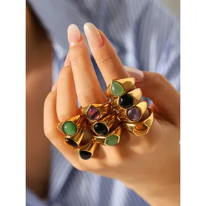 Detail view of chunky stainless steel rings featuring colorful natural stones and 18K gold finish.