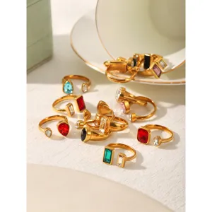 Detailed close-up view of geometric cubic zirconia open rings with colorful gemstones on fabric.