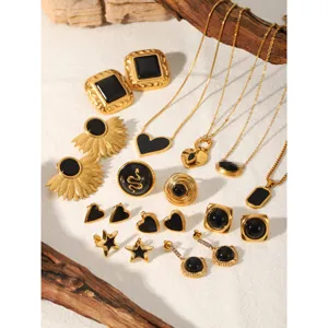 Dettaglio di gioielli in acciaio nero e oro, set di collane e anelli eleganti e chic.