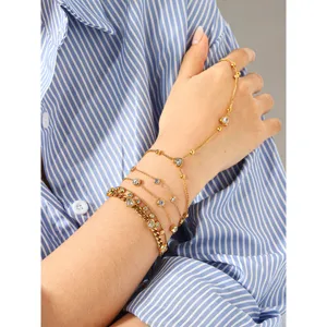 Bracelet de main multicouche doré avec zirconiums étincelants et délicats charms en forme de cœur.