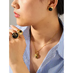 Scatto dettagliato del set di anelli serpente nero e oro, orecchini e collana cuore per donne.