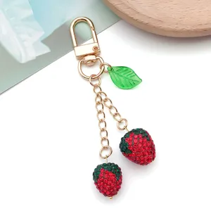 Sparkling crystal red strawberry pendant charm with green leaf and gold tone clasp keychain.