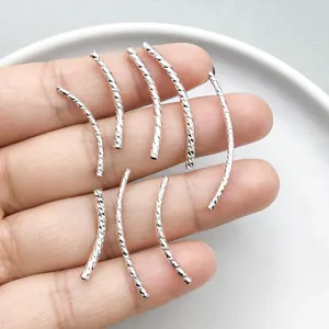 Close-up of silver-plated twisted curved tube beads for DIY jewelry making and pendants.