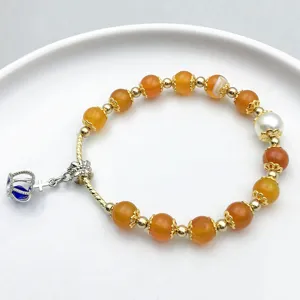 Handcrafted beaded bracelet featuring orange agate, pearl, and a charming crown pendant.