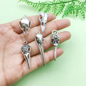 Close-up detail of vintage antique silver alloy bird skull pendants for DIY jewelry making.