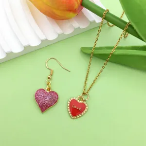 Gold-tone necklace and earring set featuring cute pink glitter and red heart enamel pendants.