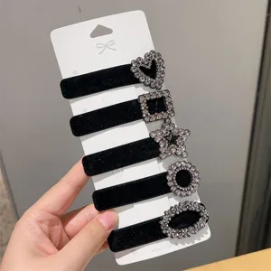 Close-up of black velvet hair clips with sparkling rhinestone geometric shapes on white card.