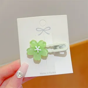 Close-up detail of a sweet green jelly flower hair clip on white card, cute side duckbill style.