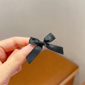 Close-up detail of a cute black ribbon bow hair clip, sweet ballet style daily hair accessory.