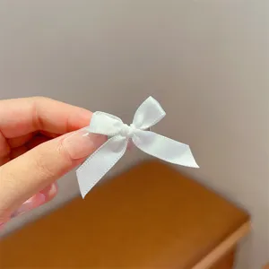 Close-up detail of a sweet white ribbon bow hair clip, delicate bow design for cute style.