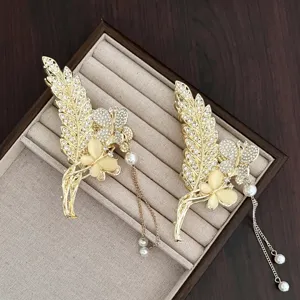 Vue détaillée de pinces à cheveux dorées vintage avec strass et pampilles de perles élégantes.