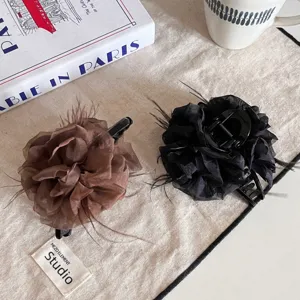Vue détaillée des pinces à cheveux élégantes en forme de fleur de plume marron et noir.