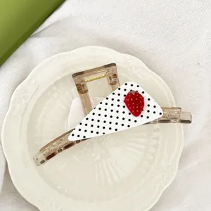 Gros plan détaillé d'une jolie pince à cheveux triangle à pois fraise au style élégant.