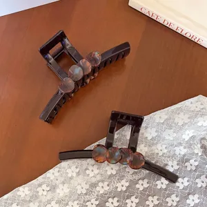 Vue détaillée de la pince à cheveux marron foncé en écaille, texture ambrée élégante.