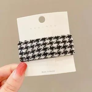 Black and white houndstooth hair clip detail close-up showing fabric texture and sturdy metal design.