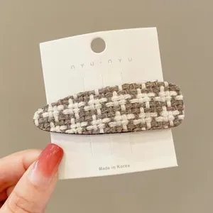 Detailed view of brown white houndstooth fabric hair clip, winter fashion side bang clip.
