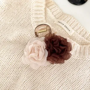 Gros plan détaillé de l'élégante pince à cheveux double rose avec des fleurs en mousseline sur tricot.