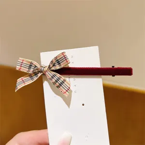 Detailed view of a sweet plaid ribbon bow hair clip with red velvet texture and card.