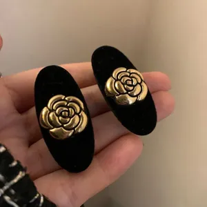 Zwarte fluwelen haarspelden met gouden camelia design, elegante vintage haaraccessoires.