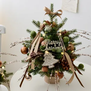 Mini tafel kerstboom met dennenappels, strikken en warme lampjes voor feestdagen.