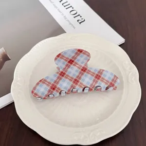 Gros plan d'une pince à cheveux chic à carreaux rouges et bleus sur une assiette.