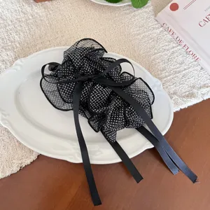 Λεπτομέρεια από μαύρο και λευκό κλιπ μαλλιών με δίχτυ πουά και μακριές κορδέλες.