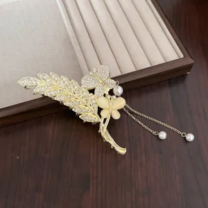 Vue rapprochée détaillée d'une pince à cheveux dorée vintage avec feuilles et perles.