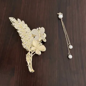 Pince à cheveux griffe en métal doré avec strass papillon et chaîne pompon perle pour chignon.
