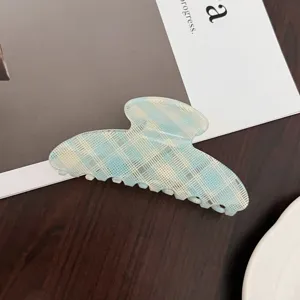 Vue en gros plan détaillée d'une élégante pince à cheveux en acétate à carreaux bleus et blancs.