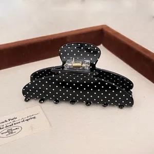 Close-up van de stijlvolle zwarte haarklem met klassieke witte stippen, mooi haaraccessoire.