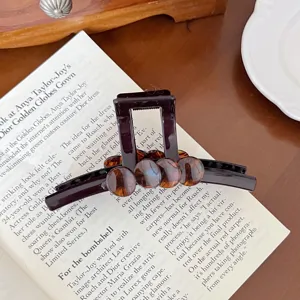 Gros plan detail de pince a cheveux ecaille de tortue en ambre marron fonce sur livre ouvert.