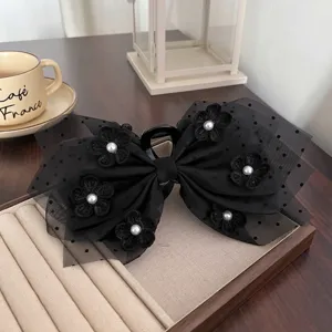 Gros plan détail de la pince à cheveux en tulle noir avec fleurs crochetées et perles.