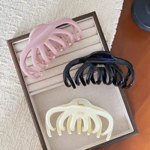 Vue détaillée de pinces à cheveux en résine rose noire et blanche sur un plateau.