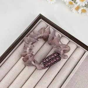 Detail de chouchou en tulle strass avec cristal carre violet scintillant et texture de tissu doux.