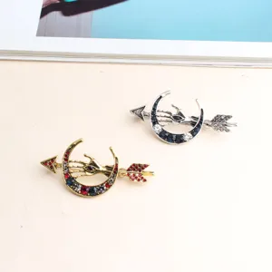 Detailed close-up of retro moon eye arrow rhinestone brooch pins in gold and silver finishes.