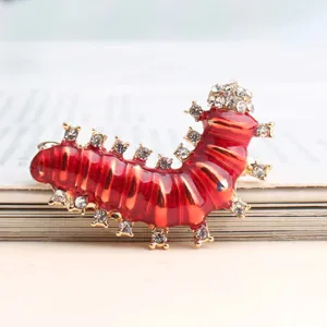 Detailopname van een charmante rode emaille rups broche versierd met sprankelende strass steentjes.