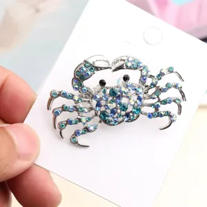 Detailed shot of a sparkling blue rhinestone crab brooch on white display card accessory.