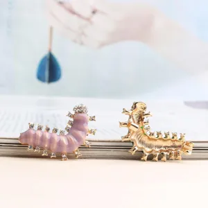 Gedetailleerd overzicht van een schattige rups broche met sprankelende strass en paarse email.