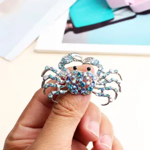 Rhinestone crab brooch detail close up view, brilliant blue crystal embellishment alloy jewelry.