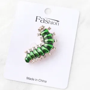 Close-up van een detail van een creatieve groene emaille strass rups broche op een displaykaart.