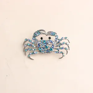 Detailed view of a sparkling rhinestone crab brooch, alloy material with blue crystals.