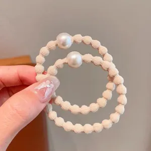 Detailopname van het stijlvolle beige parelhaarelastiek met een zachte en elastische band.