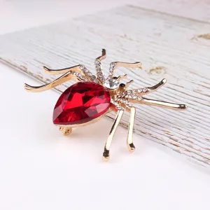 Detailopname van een prachtige spinnenbroche met een rode druppelkristal en heldere steentjes.