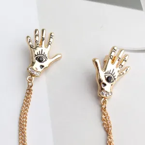 Punk vintage gold hand shape brooch pin with chain and crystal detail, fashion jewelry.