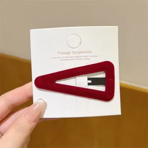 Close-up detail shot of a red velvet triangle hair clip mounted on a white display card.
