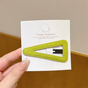 Close-up of a green velvet triangle hair clip on white card, elegant daily accessory detail.