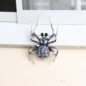 Gros plan d'une broche araignée en alliage argenté ornée de strass violets et bleus.