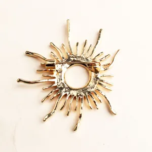 Primo piano del retro di una spilla vintage a forma di sole dorato con chiusura di sicurezza.